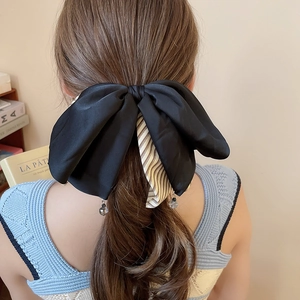 Détail de la pince à cheveux noeud en soie noire avec tissu rayé et perles de cristal