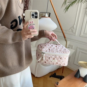 Detail of pink quilted makeup bag with bear prints and sturdy top handle for travel