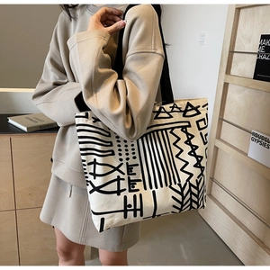 Detailed close-up of thick canvas tote bag with black abstract geometric art patterns
