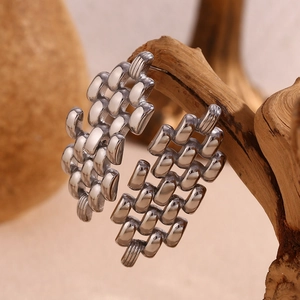 Macro detail of silver-toned chain strap earrings hung on a rustic wooden stand