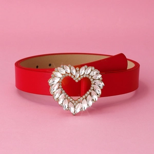 Macro shot of a red leather belt featuring a heart-shaped buckle with sparkling crystals