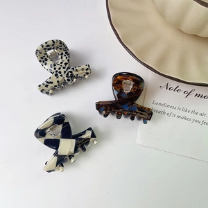 Three acetate hair claws in leopard, checkered, and spotted patterns for styling