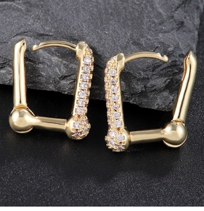 Detailed macro view of gold geometric huggie earrings with sparkling zircon inlay