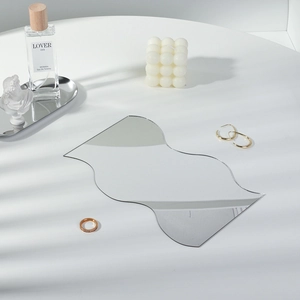 Close-up of wavy acrylic mirror tray with decorative candles and luxury gold jewelry