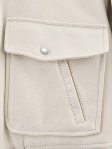 Détail de la poche à rabat et du bouton décoratif sur la veste beige en laine