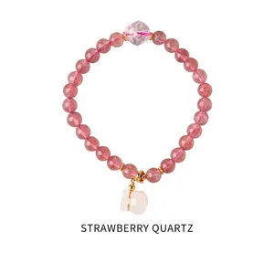 Close-up of strawberry quartz beaded bracelet with a white cat charm and golden metal parts
