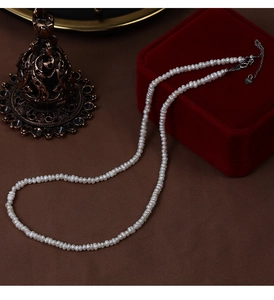 Detail view of irregular freshwater pearl necklace on red velvet box with heart pendant