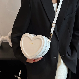 Dettaglio della borsa a tracolla bianca a forma di cuore con scritte dorate e fibbia