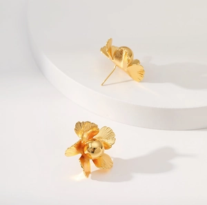 Detailed macro view of 18K gold plated brass floral stud earrings on white pedestal