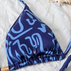 Detail of blue printed halter bikini top with golden metallic rings and ruched texture