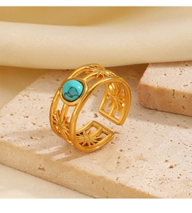 Detail of gold-plated starburst cut-out ring with turquoise stone on stone texture