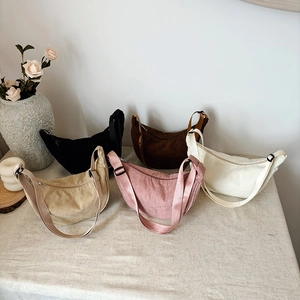 Corduroy crossbody tote bags in five colors with adjustable straps on a rustic table