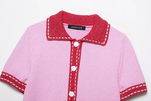 Detail view of pink and red knit top featuring contrast collar and white buttons