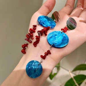 Detail of long tassel earrings with blue marble discs and red stone bead strands
