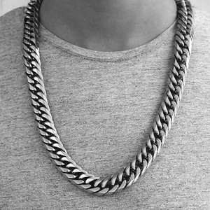 Close-up of a silver chunky Cuban link stainless steel necklace worn by a male model