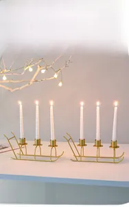 Golden sleigh-shaped metal candle holders with white spiral candles for festive decor