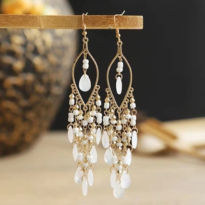 Close-up of bohemian long tassel earrings with golden frame and beads on wood stand