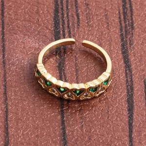 Macro detail of gold open ring with green and white heart-shaped zircon stones