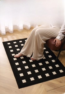Close-up of black and white checkered floor mat with a brown leather chair in a room