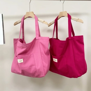 Close-up of pink and rose red canvas tote bags with front pockets and brand labels
