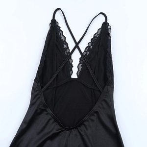 Détail des bretelles croisées et dentelle délicate sur une nuisette en satin noir