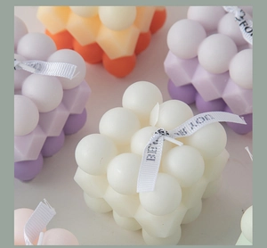 Detailed top view of cube bubble candles in white, purple and orange with silk ribbons