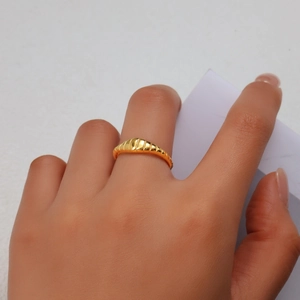 Vue détaillée d'une bague croissant dorée avec des rayures texturées sur le doigt
