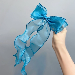 Close-up of blue organza double-layered bow hair clip with shimmering metallic fabric texture