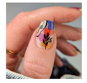Detailed view of long oval press-on nails with colorful abstract art and black leaf motifs