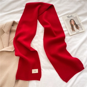 Classic bright red knitted wool scarf with emo tag on a minimalist background