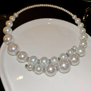 Close-up of elegant gradient white pearl choker necklace with silver beads on a white plate
