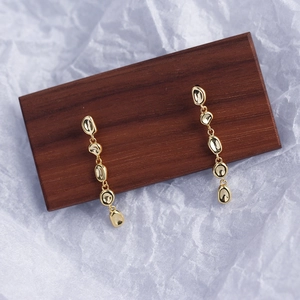 Detailed view of irregular gold circular metal discs in a cascading fringe earring design