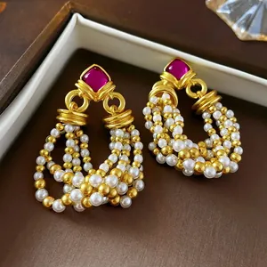 Vintage style drop earrings with magenta gemstone and faux pearl tassels in a 45-degree view