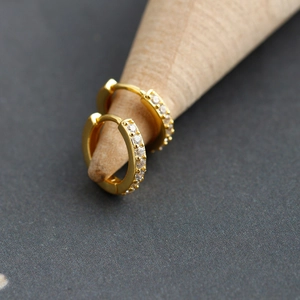 Macro shot of gold huggie earrings with sparkling pavé cubic zirconia inlay detail