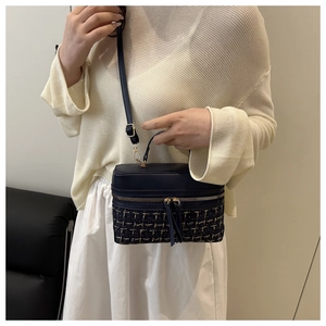 Detail of tweed and leather crossbody box bag shown on model with shoulder strap