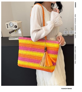 Detail of colorful striped straw tote bag with wood bead tassel and woven shoulder strap