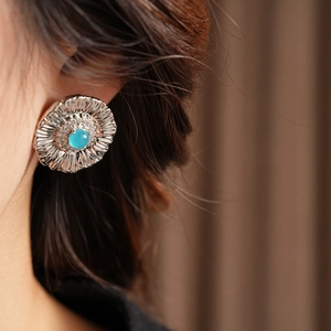 Detailed close-up of a vintage floral silver stud earring with turquoise and zircon