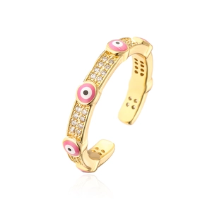 Macro shot of gold-plated open ring with pink enamel evil eye and sparkling zircons