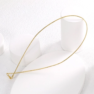 Minimalist gold fine chain necklace displayed on white geometric props for a luxury aesthetic