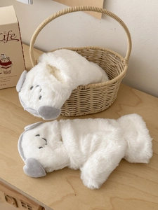 Detail of plush white dog-shaped gloves with cute ears in a cozy wicker basket setting