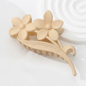 Macro detail of cream floral hair claw clip featuring matte resin texture and flower shape