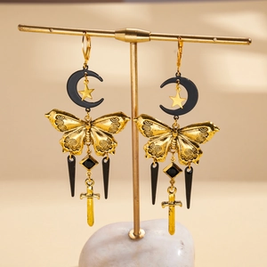 Detail of gothic moon and star earrings with golden butterfly and sword charms