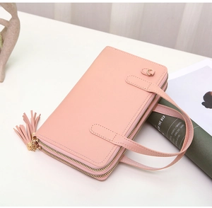 Pink double zipper wallet with fringe detail and gold hardware on white surface