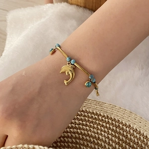 Detailed view of ocean theme gold turtle bracelet with blue beads on a model's wrist