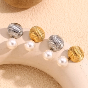 Detailed close-up of gold and silver hot air balloon earrings with white pearl pendants