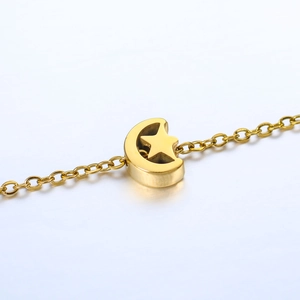 Detail of golden stainless steel bracelet featuring star and moon charms on a link chain