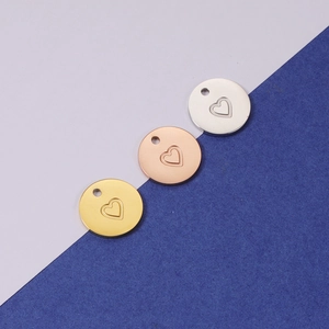 Vue détaillée de pendentifs ronds gravés d'un cœur en finitions or, rose et argent