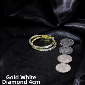 Detailed view of 4cm gold hoop earrings with white crystals on black satin silk