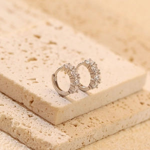 Macro detail of S925 silver hoop earrings with shimmering cubic zirconia stones on stone