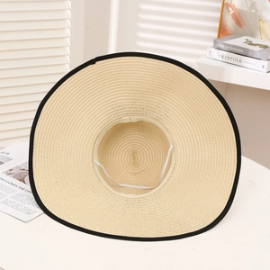 Detail of light beige straw hat with black brim binding and white elastic chin strap